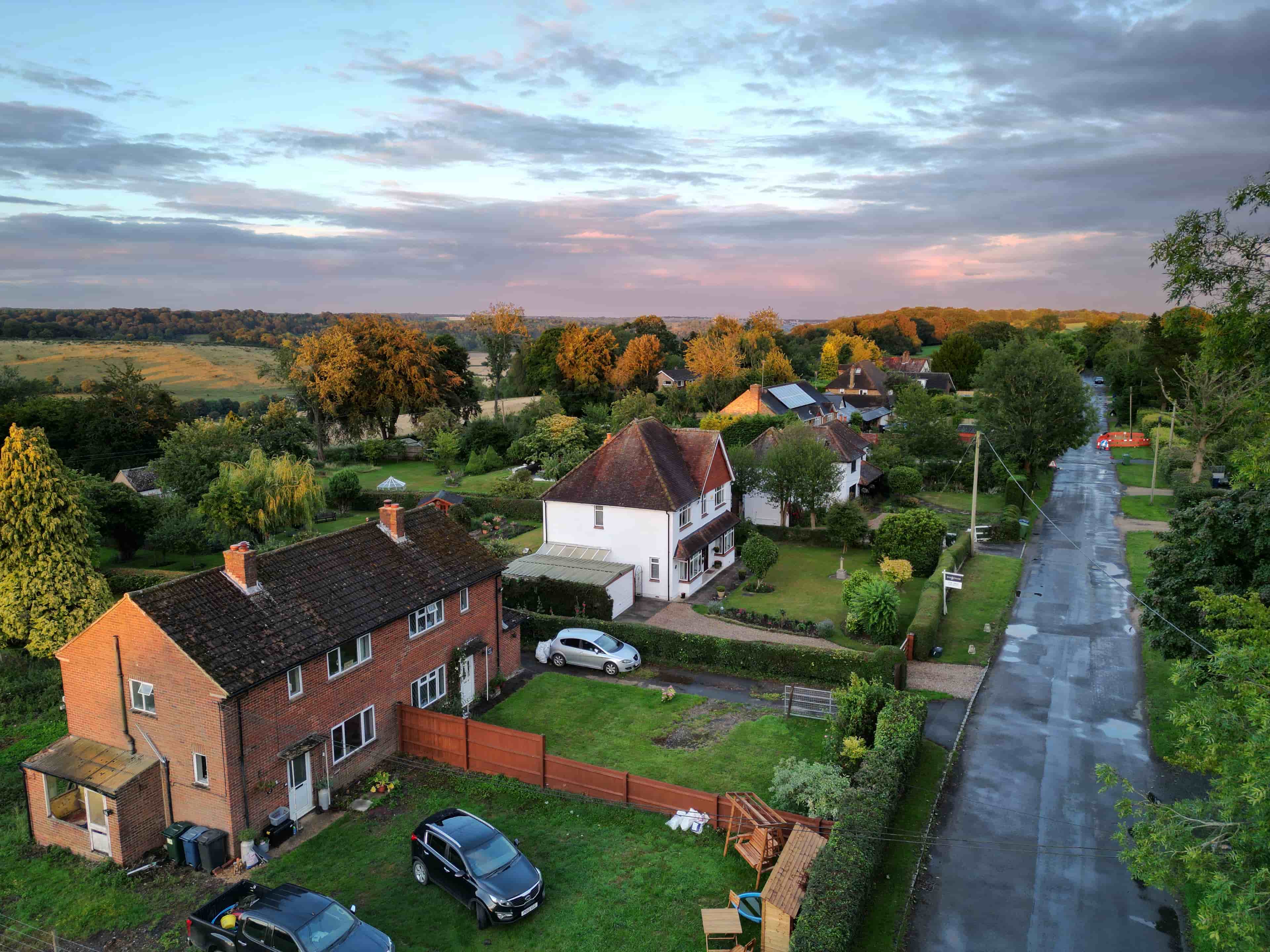 A golden-hours drone photo of a white house property for sale