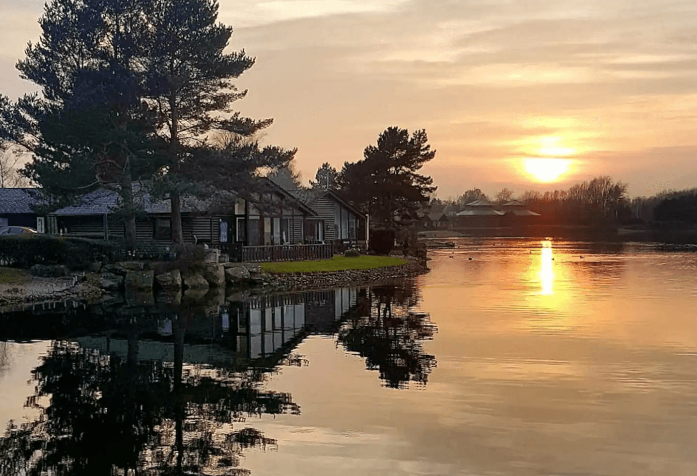 An aerial shot of a sunset over a lake and a house