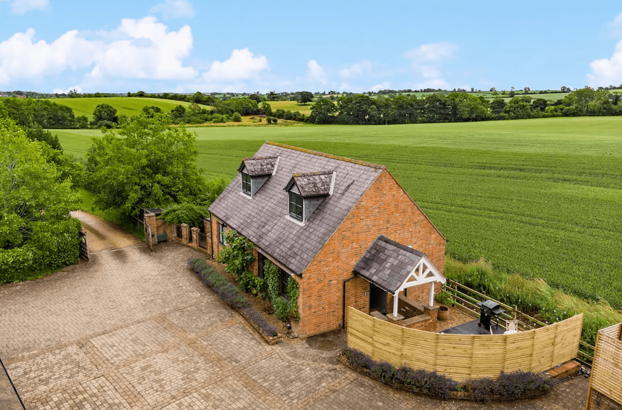 A drone photo of a country house surrounded by countryside and green open fields